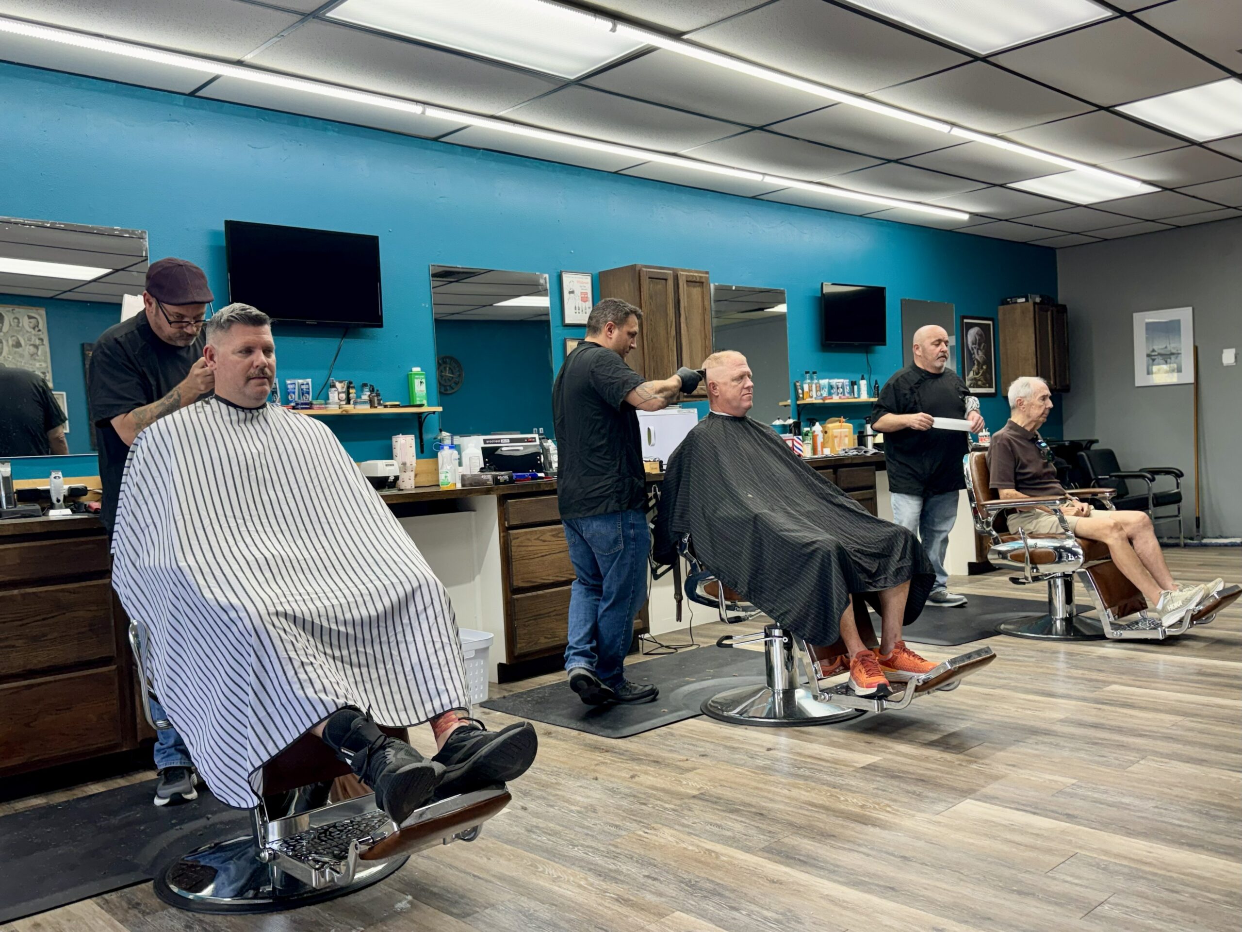 Barbers working with clients at Venice Barbershop in Florida, blue collar and older men receiving haircuts in a welcoming, traditional shop atmosphere